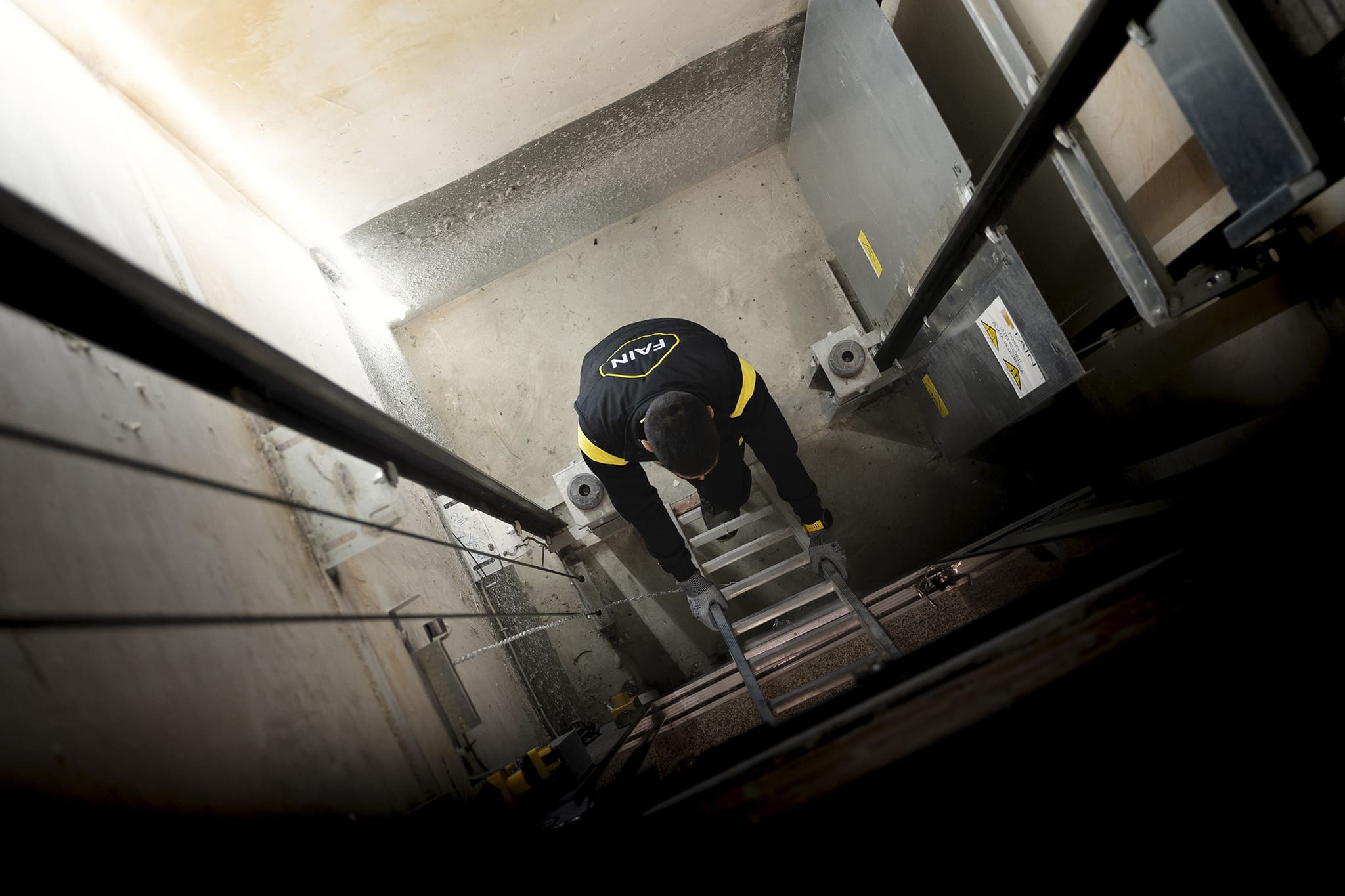 Técnico FAIN subiendo escalera para arreglar un ascensor